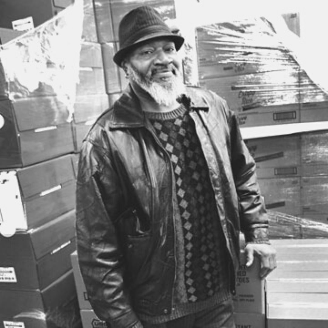 A man wearing a hat and leather coat in a warehouse