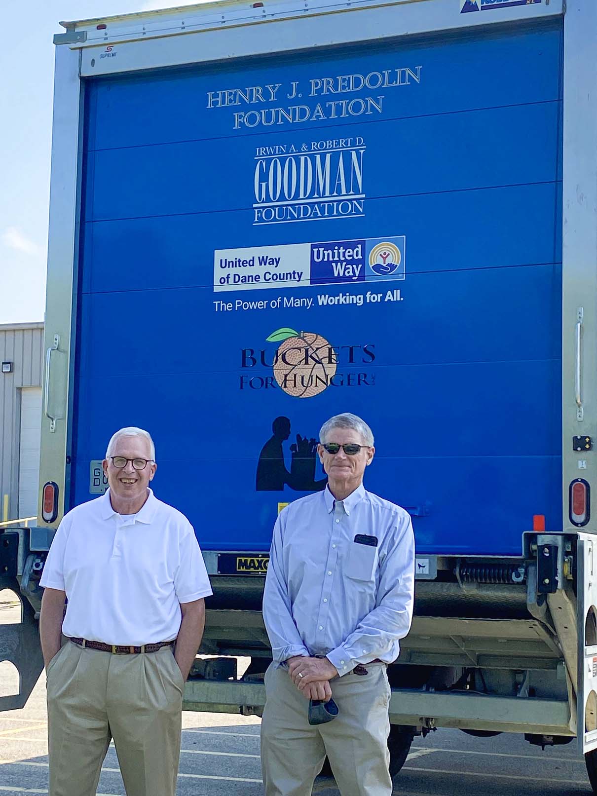 Two men standing in front of a refrigerated truck
